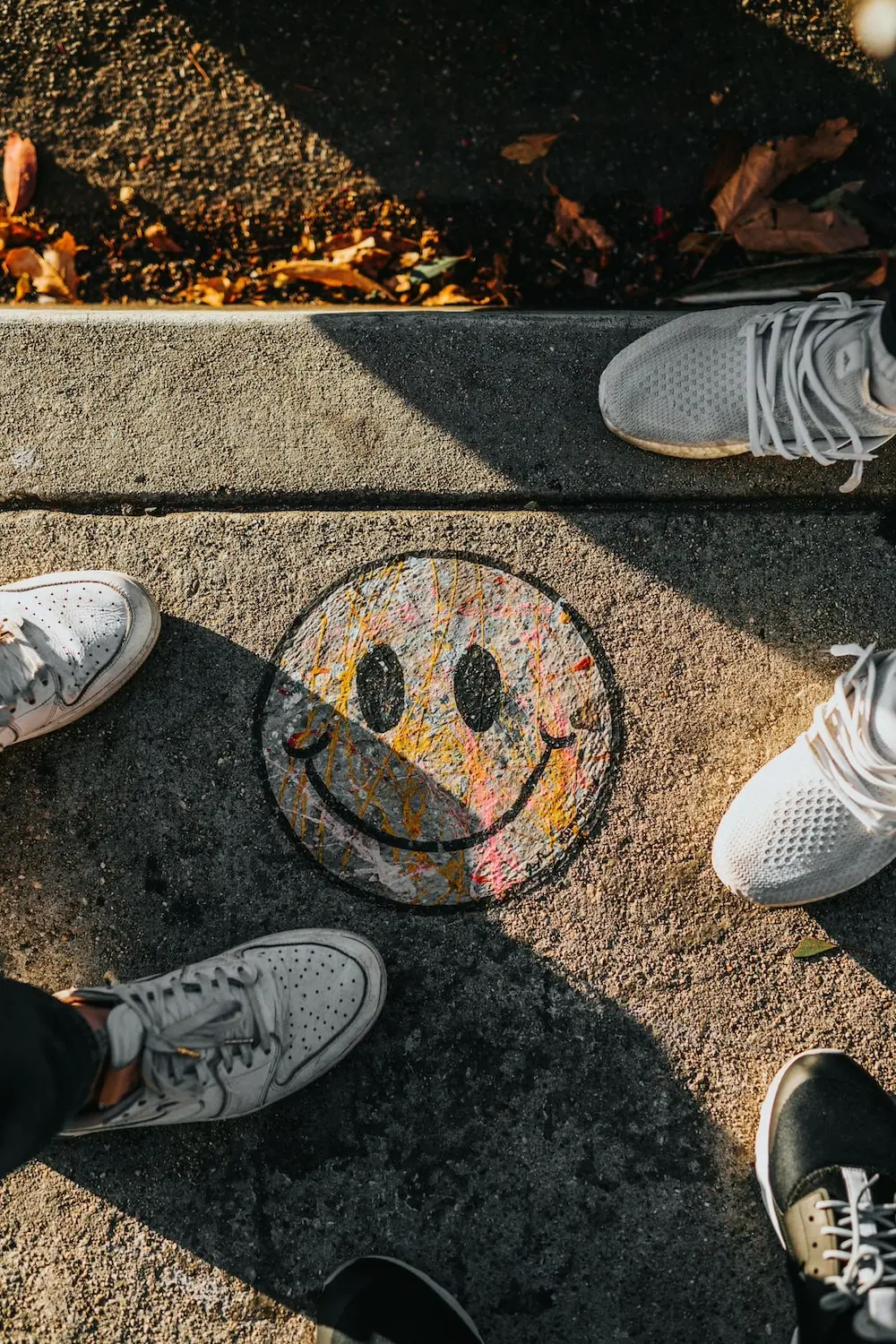 Bunter Smiley auf Straßenboden, um den Personen drumherum stehen